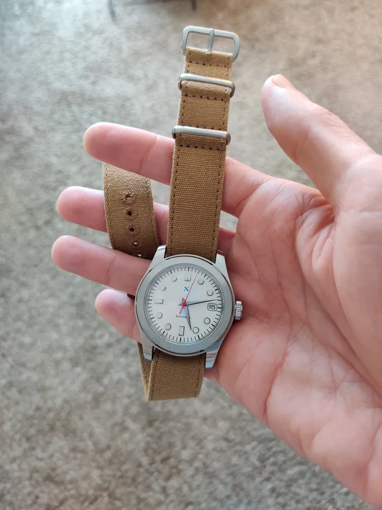 Holding a watch with a tan NATO strap